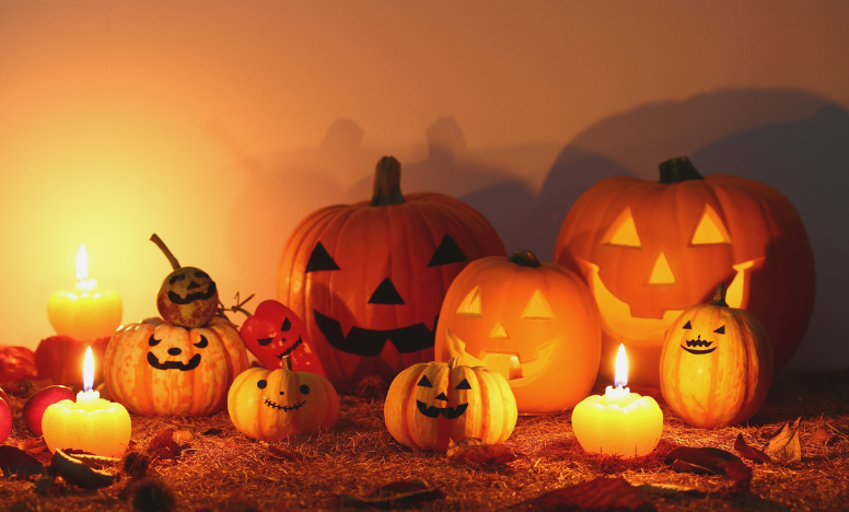 A collection of Halloween pumpkins with candles, featuring carved jack-o'-lantern faces glowing in the dark.
