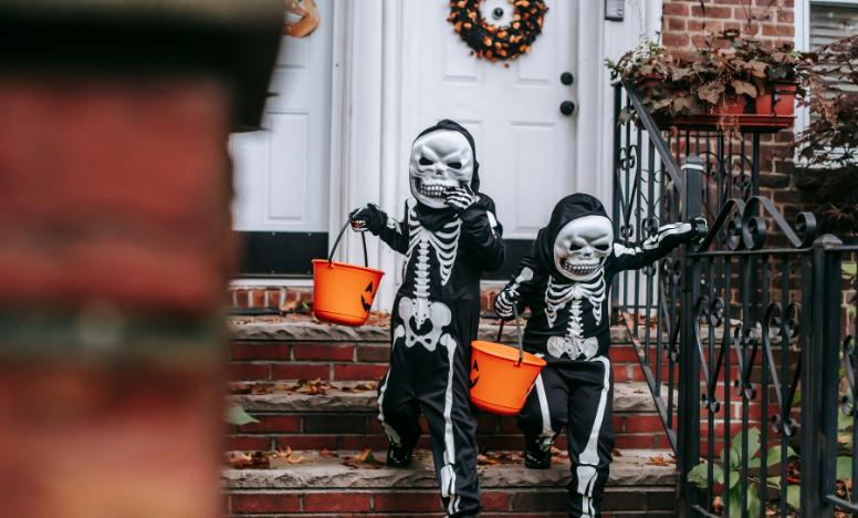 Two children in skeleton costumes walk down the steps, excited for Halloween festivities